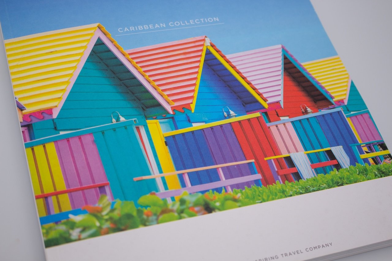 the front cover of a holiday brochure with brightly coloured wooden sea hut