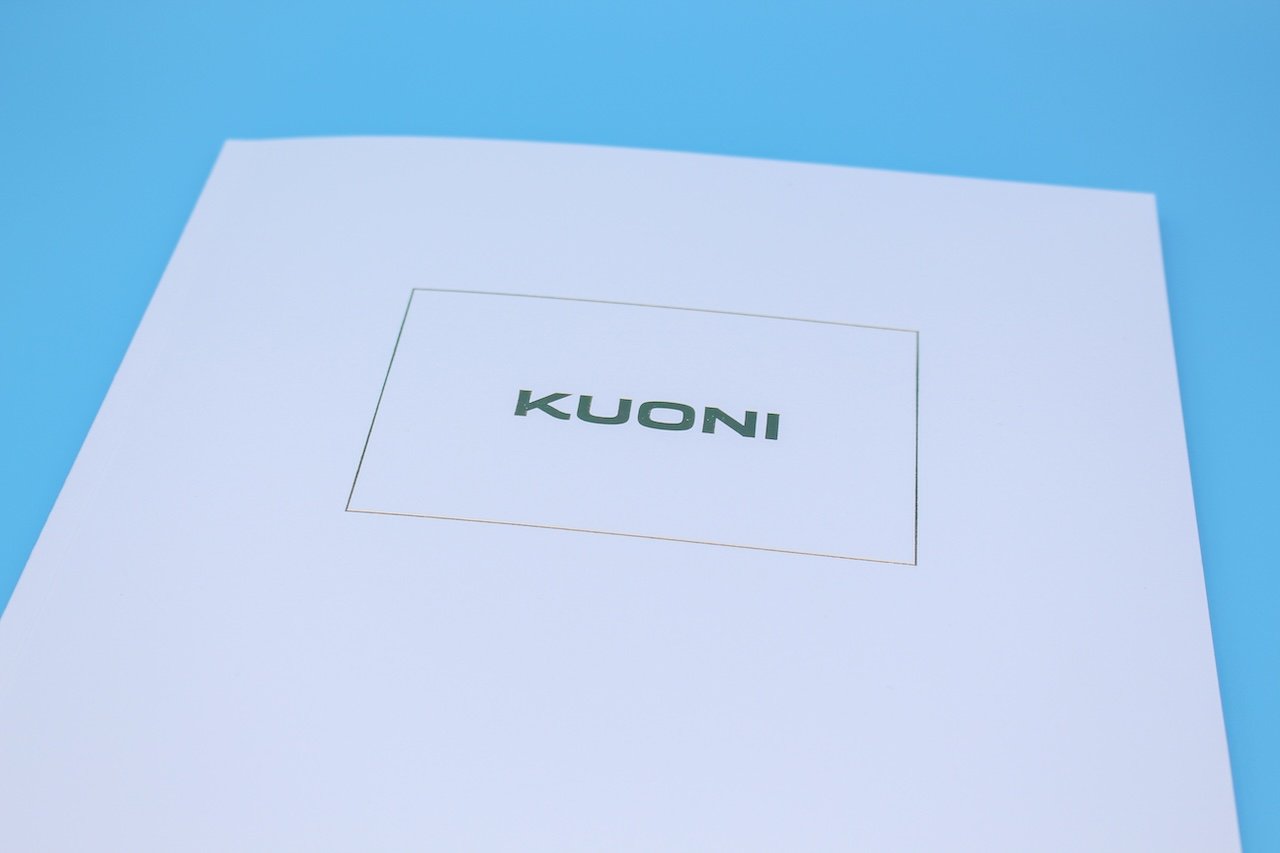 the front page of a white travel brichure with the word kuoni on the front in gold foil